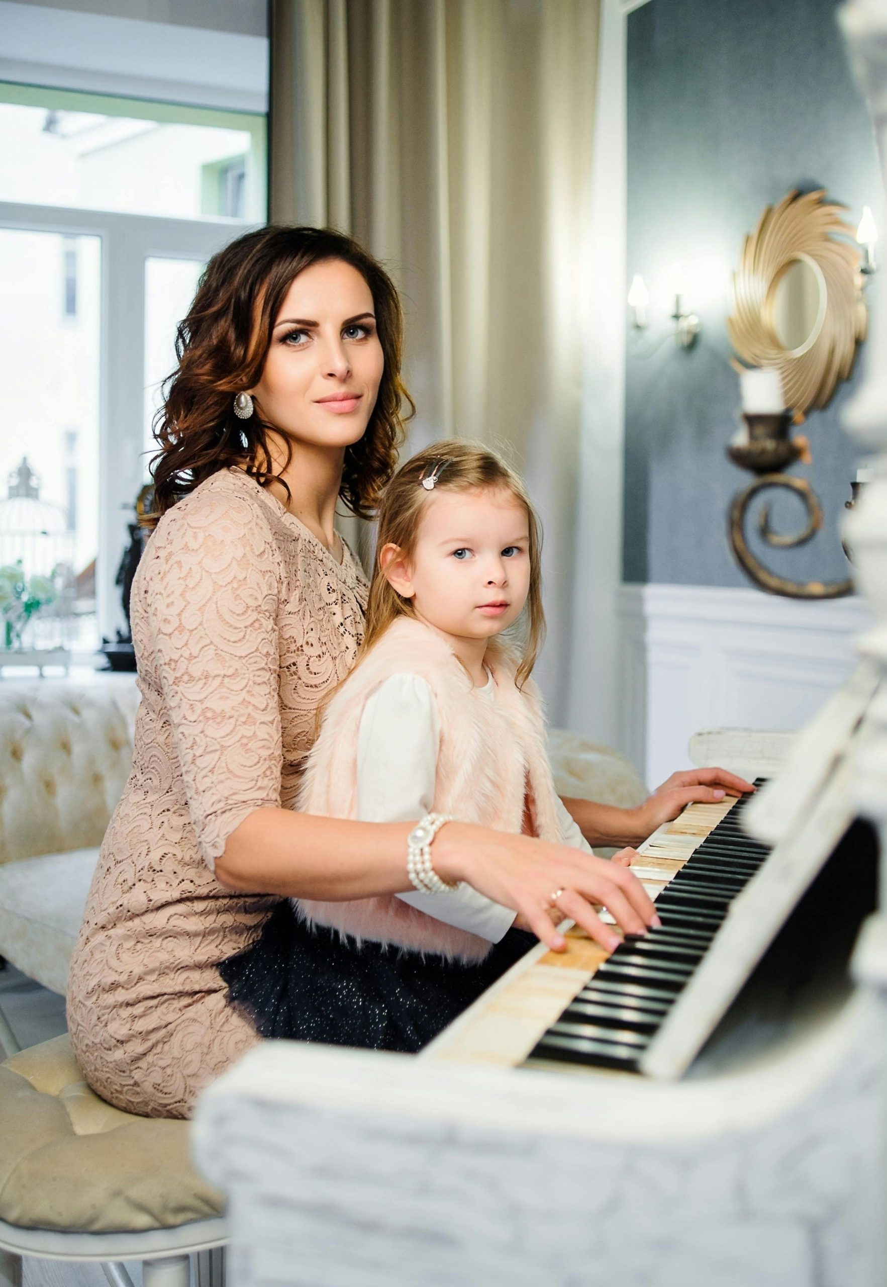 Elegant mother and daughter playing piano together, showcasing family bond.